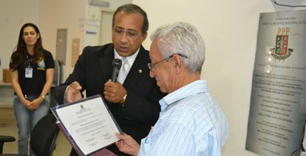 Foto do mesário voluntário, Mário Evangelista, recebendo placa de homenagem.