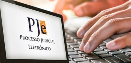 TSE-PJe-1-grau Foto de um computador com as mãos do usuário no teclado e o texto Processo Judicial Eletrônico